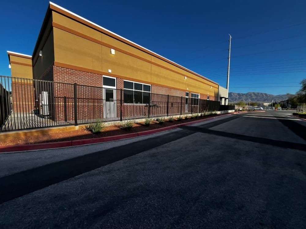 Commercial building with brick exterior and fenced area, set against a clear blue sky.