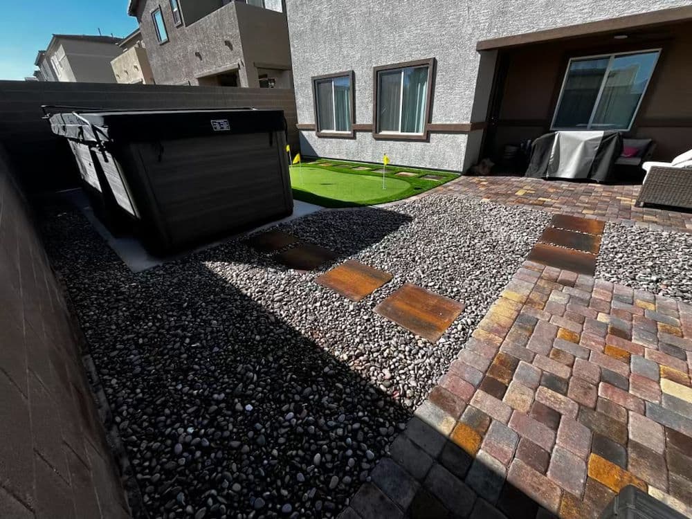 Modern backyard design featuring stones, grass, and a large trash bin for outdoor living.