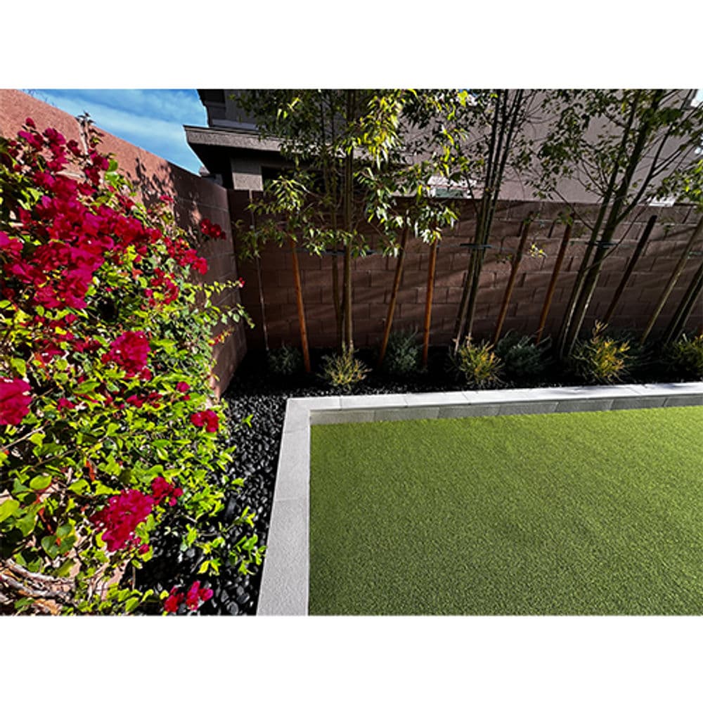 Vibrant garden with bougainvillea, brick wall, and lush artificial turf in a landscaped yard.