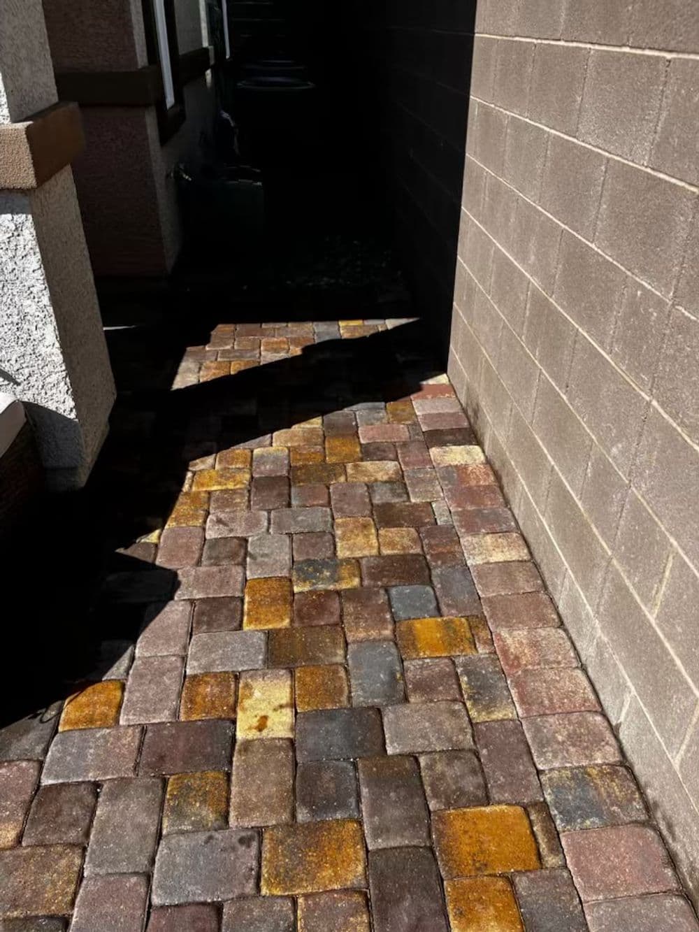 Colorful brick walkway in a narrow alleyway, featuring shades of brown and yellow.